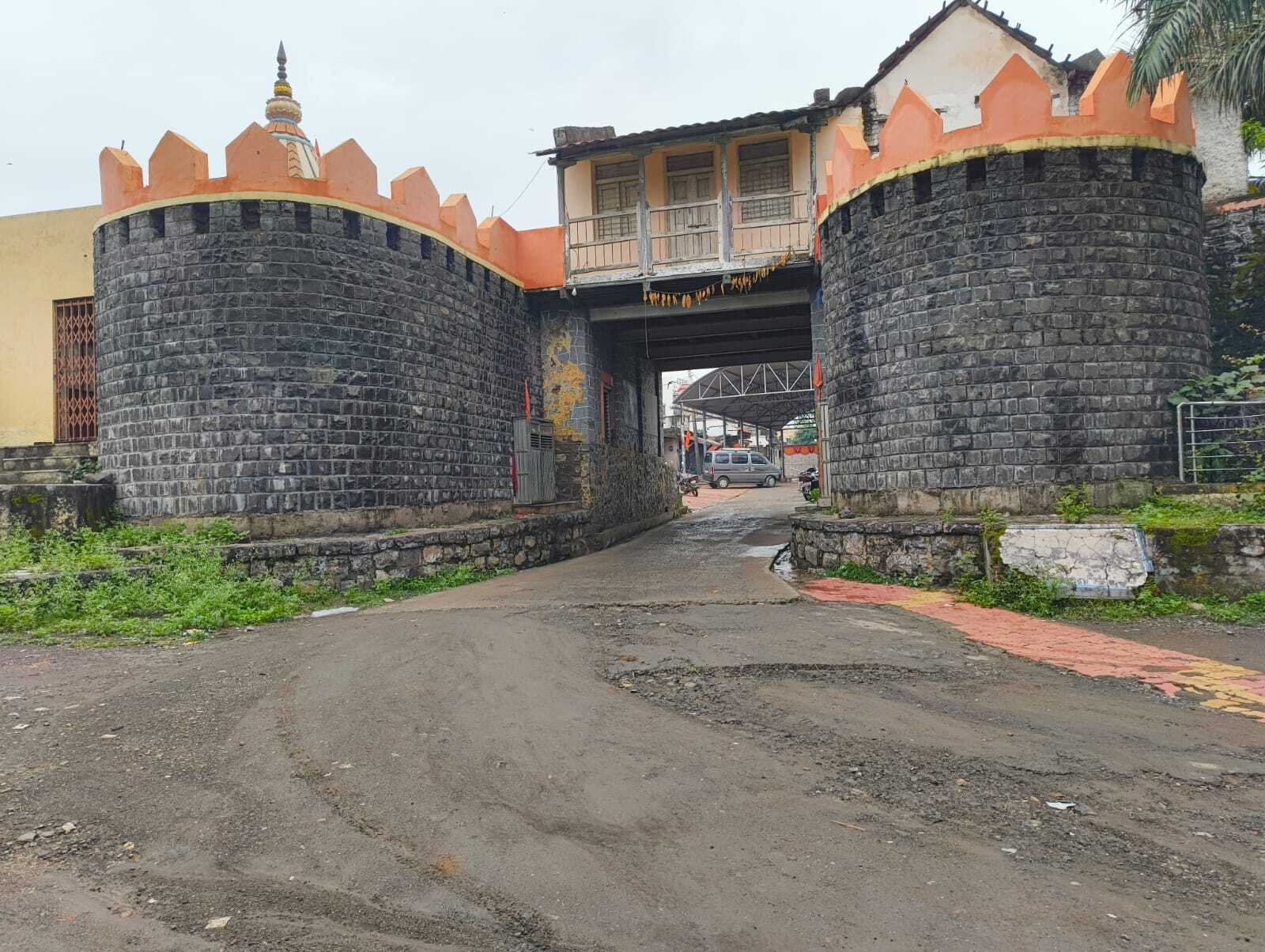 दगडी बांधकाम असलेले भव्य गाव प्रवेशद्वार, दोन्ही बाजूंनी गोल बुरुज, वरती गडकोट शैलीतील कड्या व रंगीत कमानी.